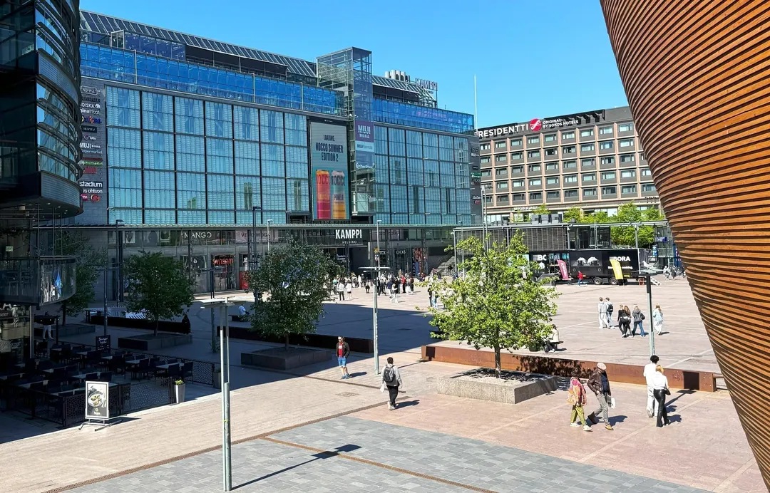 People crossing the open paving of Narinkkatori square in central Helsinki on a bright afternoon