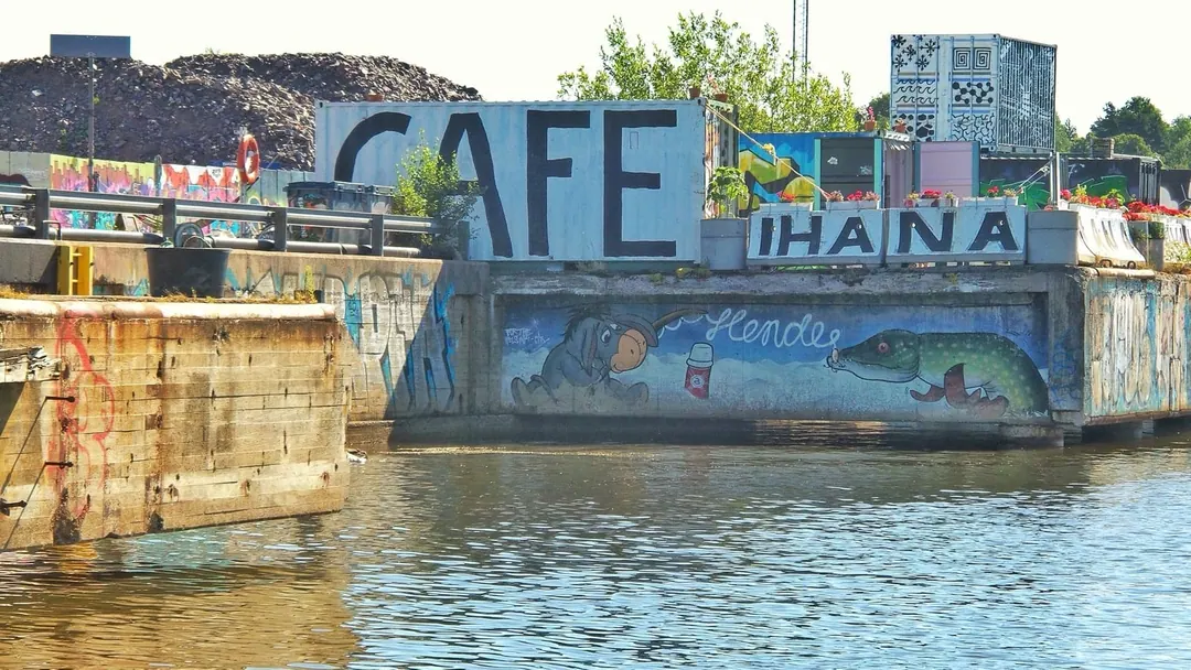 The hand-painted Cafe Ihana sign beside the water in Sompasaari, Helsinki