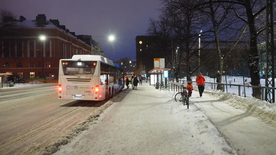 A bus at a stop on Hämeentie in the blue dusk of a January afternoon