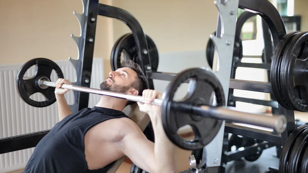 A man mid-set on a bench press under a loaded bar