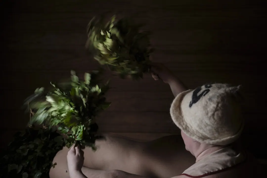 A bather being whisked with leafy birch twigs in a sauna