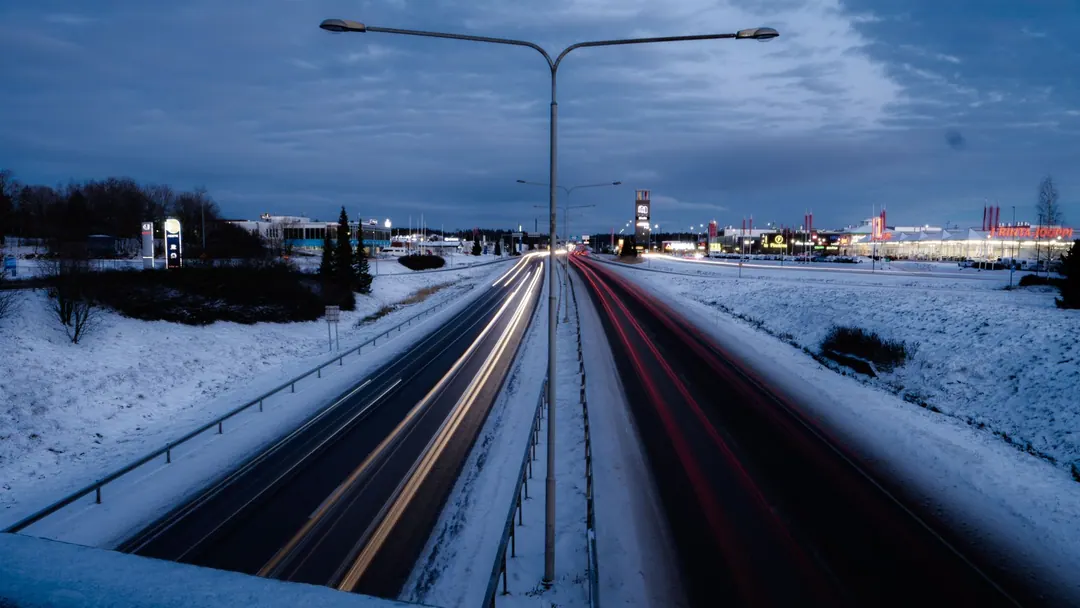 Long-exposure car light trails on a snowy highway in Raisio