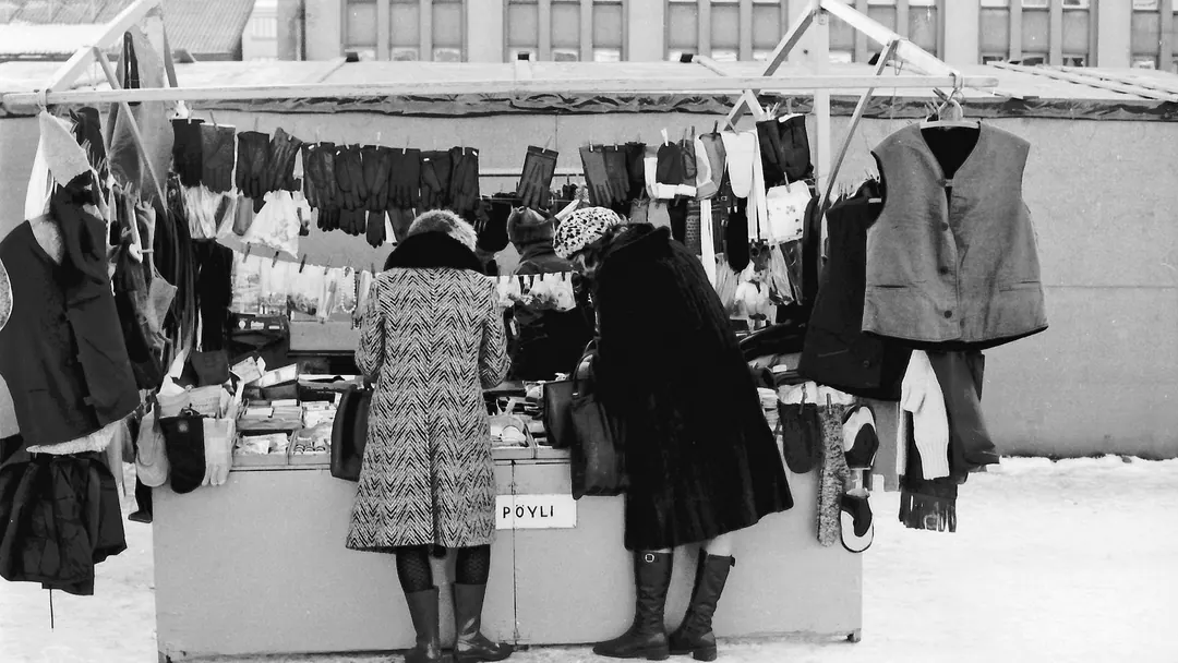 Two women looking through clothes at a market stall in winter, 1975