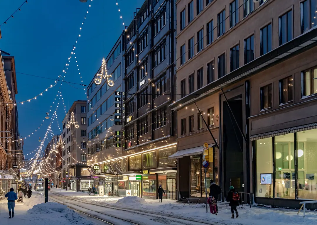 Aleksanterinkatu at night in January, snow banked along the tram tracks and lights strung across the street