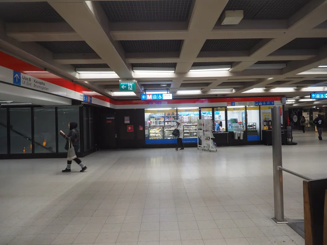 The Asematunneli concourse under Helsinki Central Station, an R-kioski lit at the far end and one person crossing the empty floor
