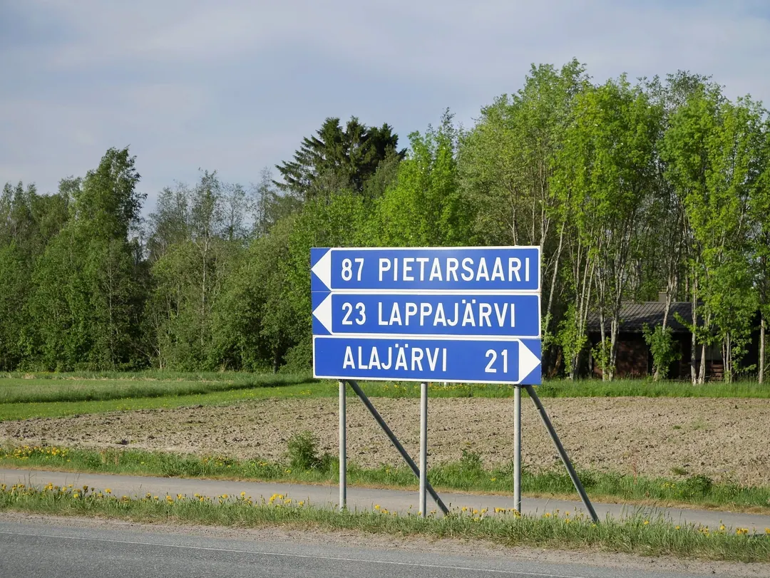 A blue Finnish road sign listing Pietarsaari 87, Lappajärvi 23 and Alajärvi 21 with distances