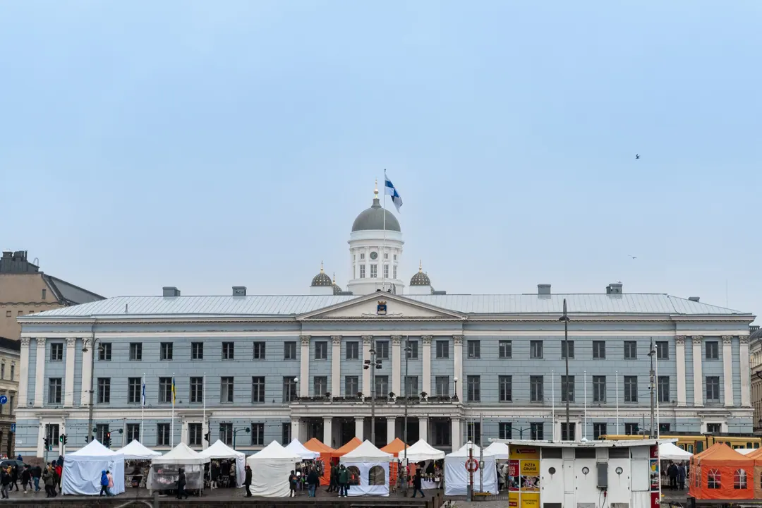 Helsinki City Hall behind a row of white and orange market stalls on the market square