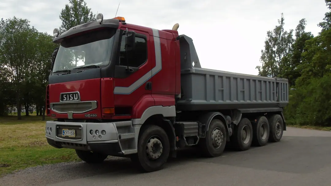 A red Sisu tipper truck with the brand name across the grille, parked on a verge