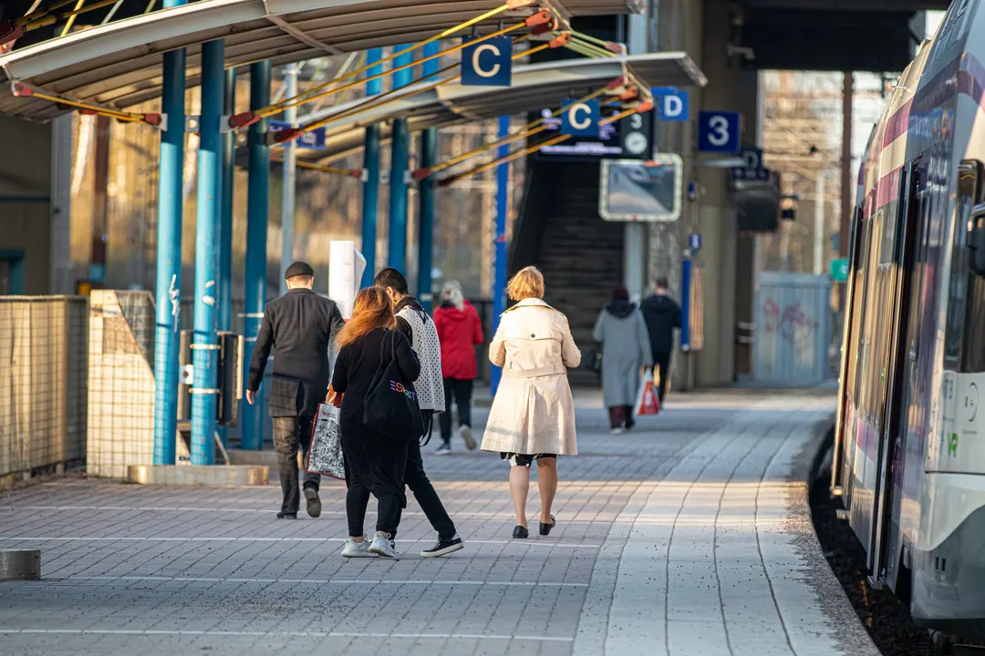 Passengers walking away from a train at Käpylä station in Helsinki in the evening, spaced well apart