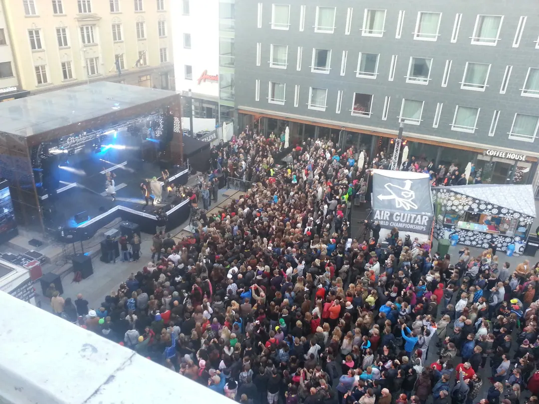 The crowd at the Air Guitar World Championships in Oulu, seen from above, with the stage and the banner at the far end of the square