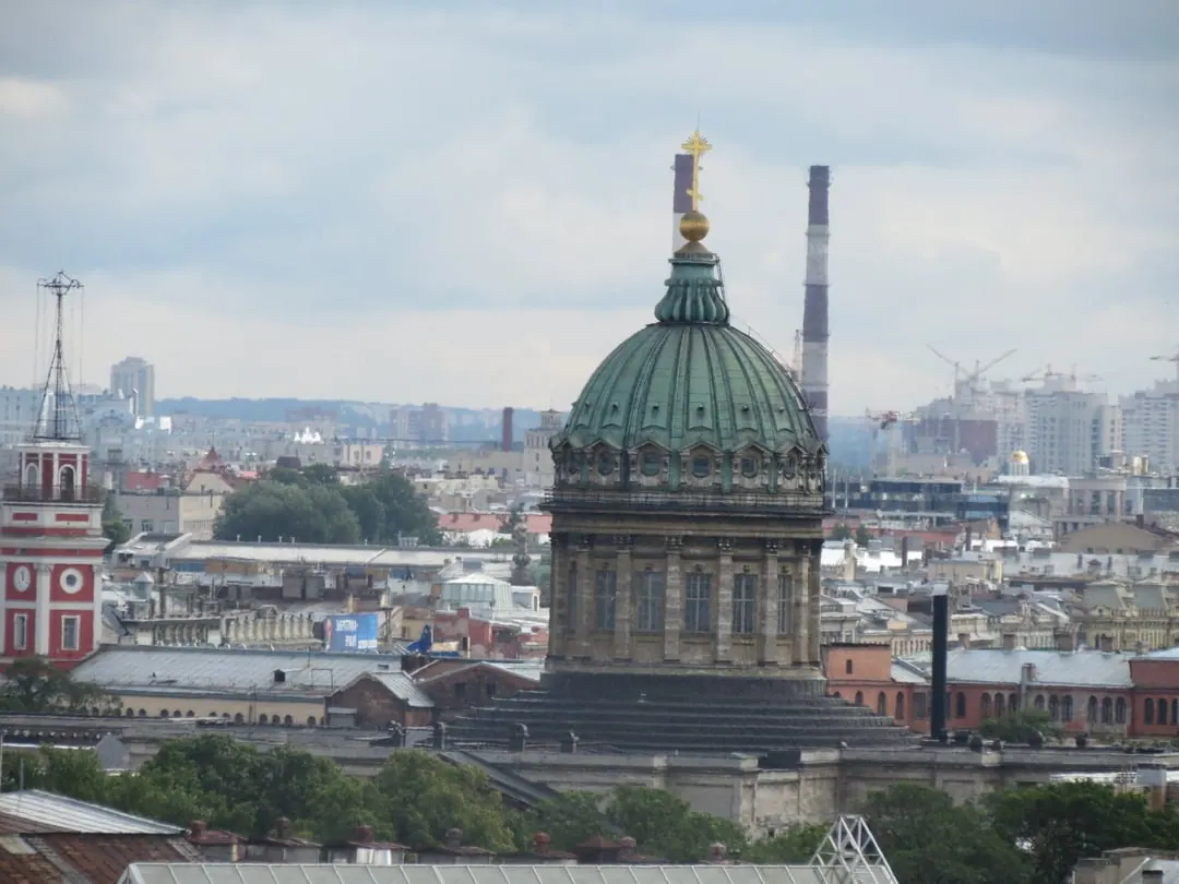 A grey-green domed cathedral rising above a city skyline, with a single large dome on a drum