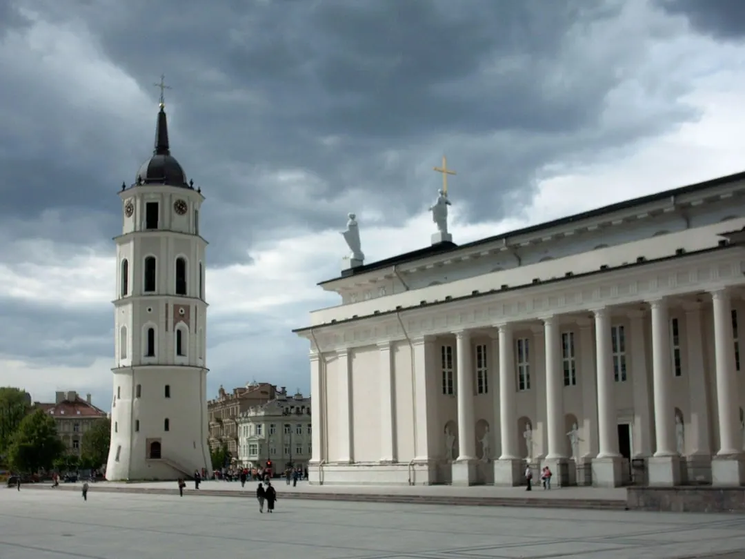 A white neoclassical cathedral with a columned portico and a separate free-standing white bell tower beside it