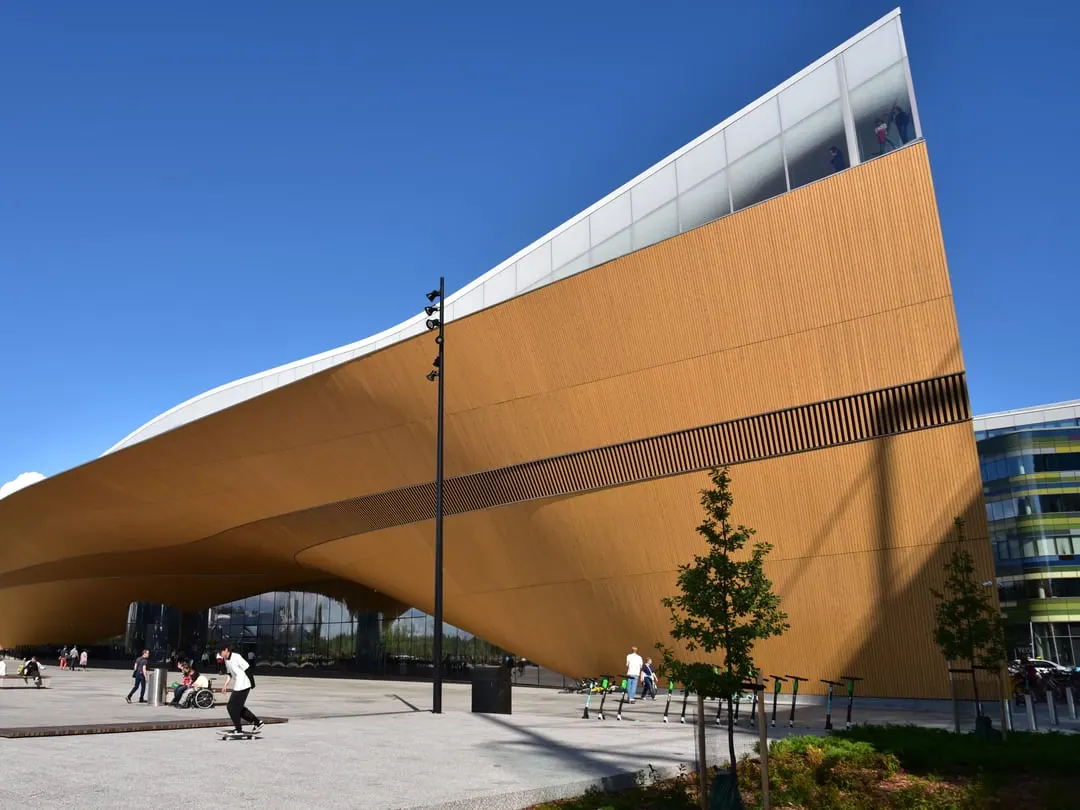 A public library with a curved timber-clad underside sweeping up from the ground and a glass upper floor