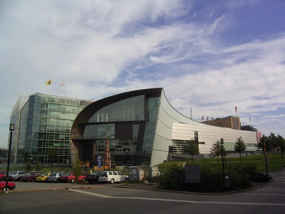A museum with a long curved metal-clad roof sweeping over a glass and steel facade