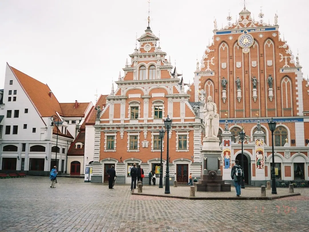 An ornate stepped-gable brick building with elaborate stonework facing a paved square