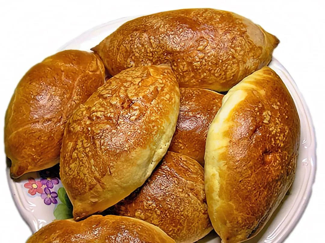 A plate of plump golden baked buns with sealed seams and no visible filling