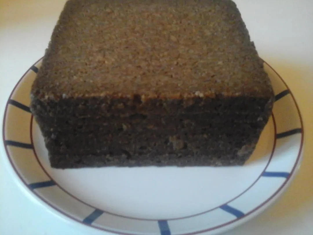 A dark brown rectangular loaf with a damp even crumb and no crust, on a plate