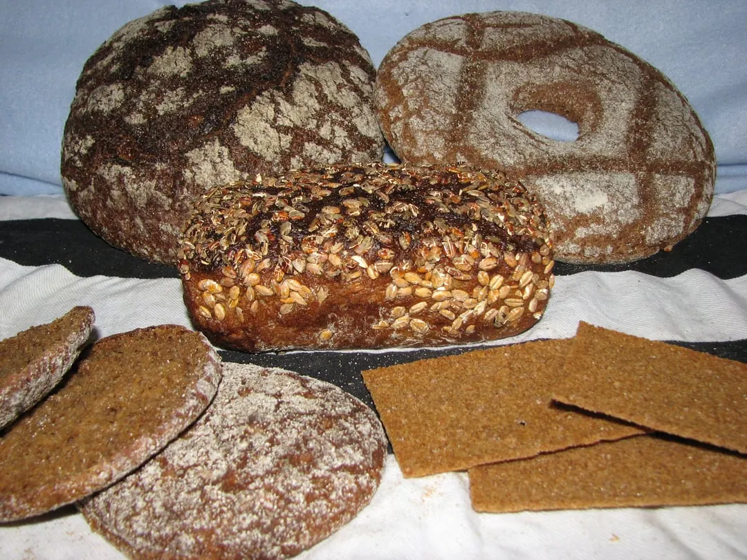 Round dark rye loaves, one with a hole through the middle, stacked beside thin rye crispbread and cut slices