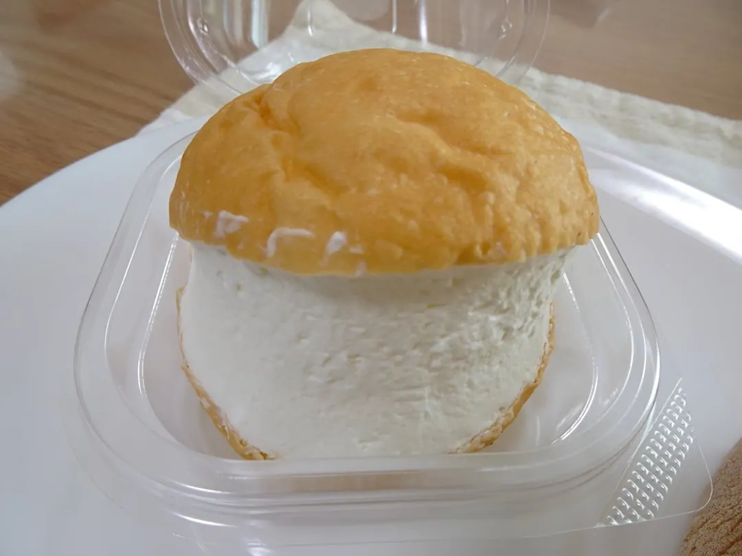 A soft round bun split and packed with a thick slab of plain whipped cream, in a plastic pack