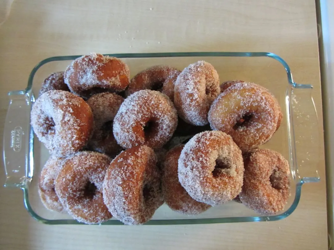 A glass dish of sugared ring doughnuts