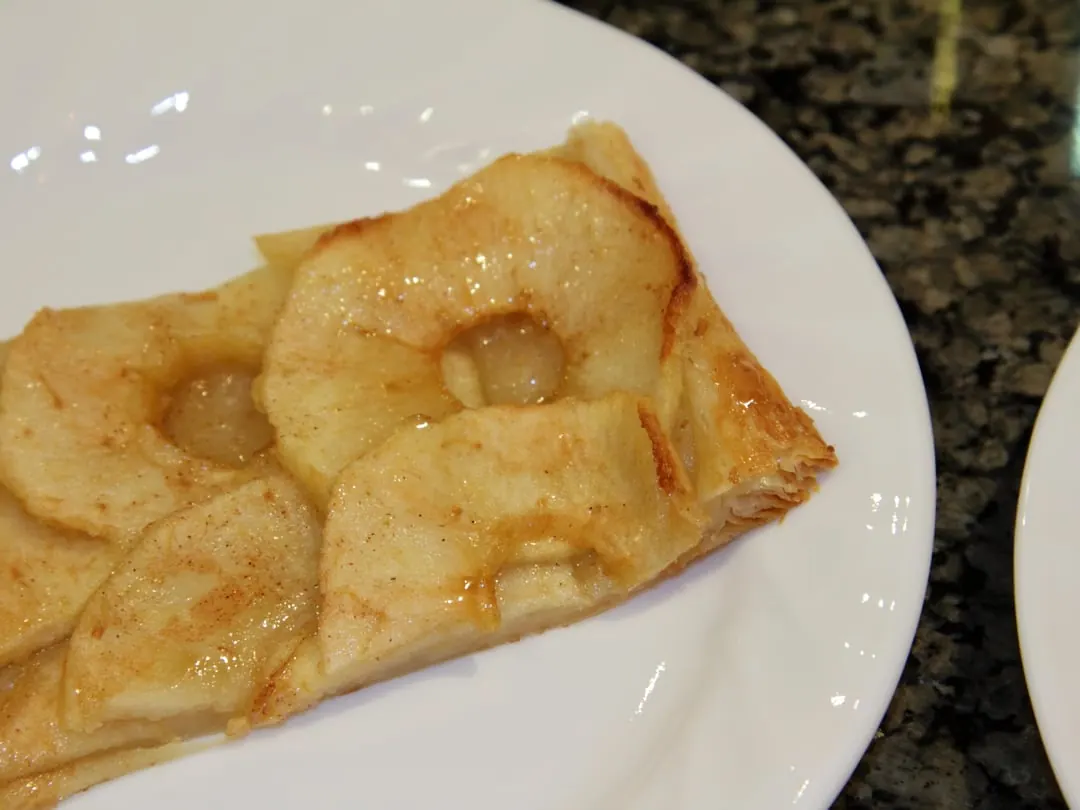 A flat free-form pastry with overlapping apple slices and edges folded roughly inwards