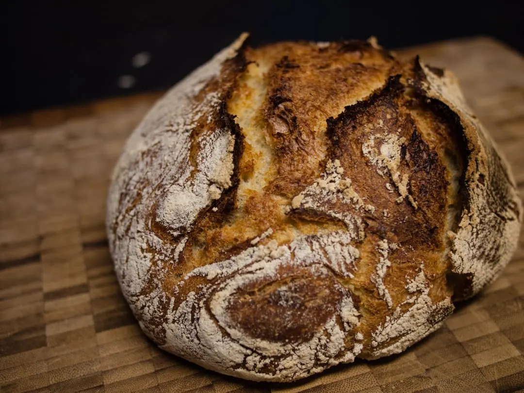 A round crusty sourdough loaf scored deeply across the top