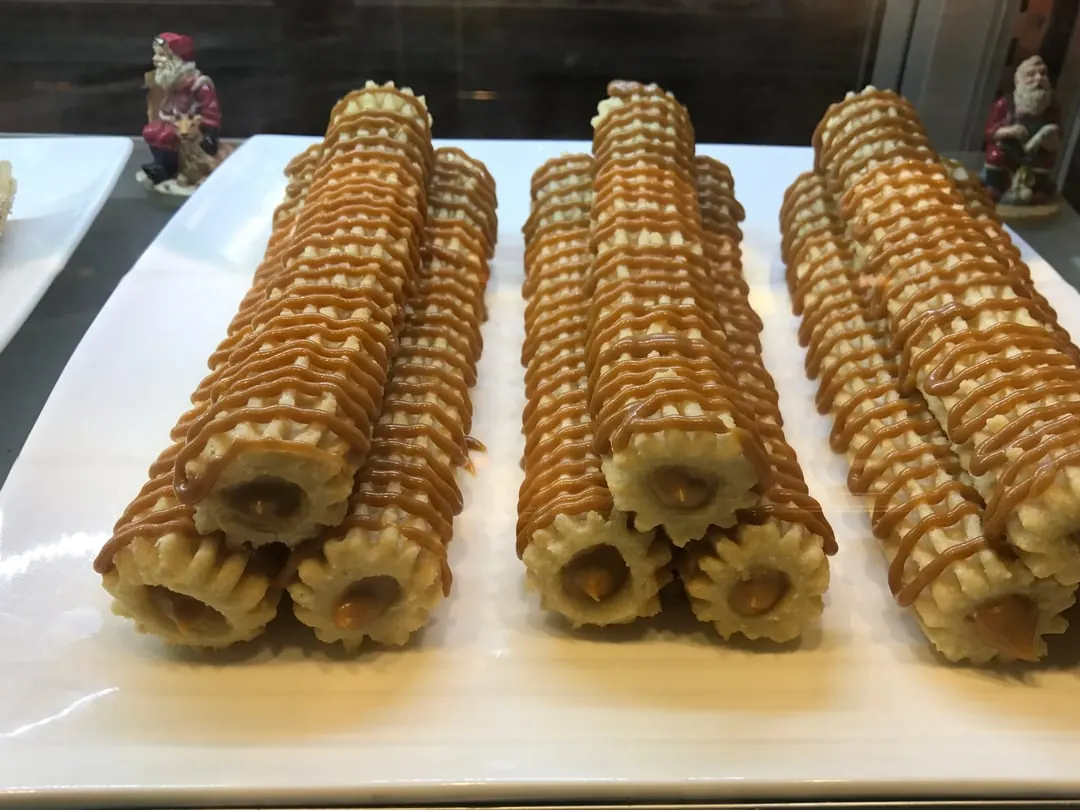 Three long straight ridged churros standing upright in a rack