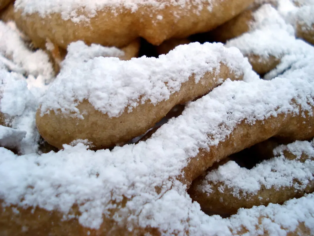 Flat lacy ribbons of fried batter under a heavy dusting of powdered sugar