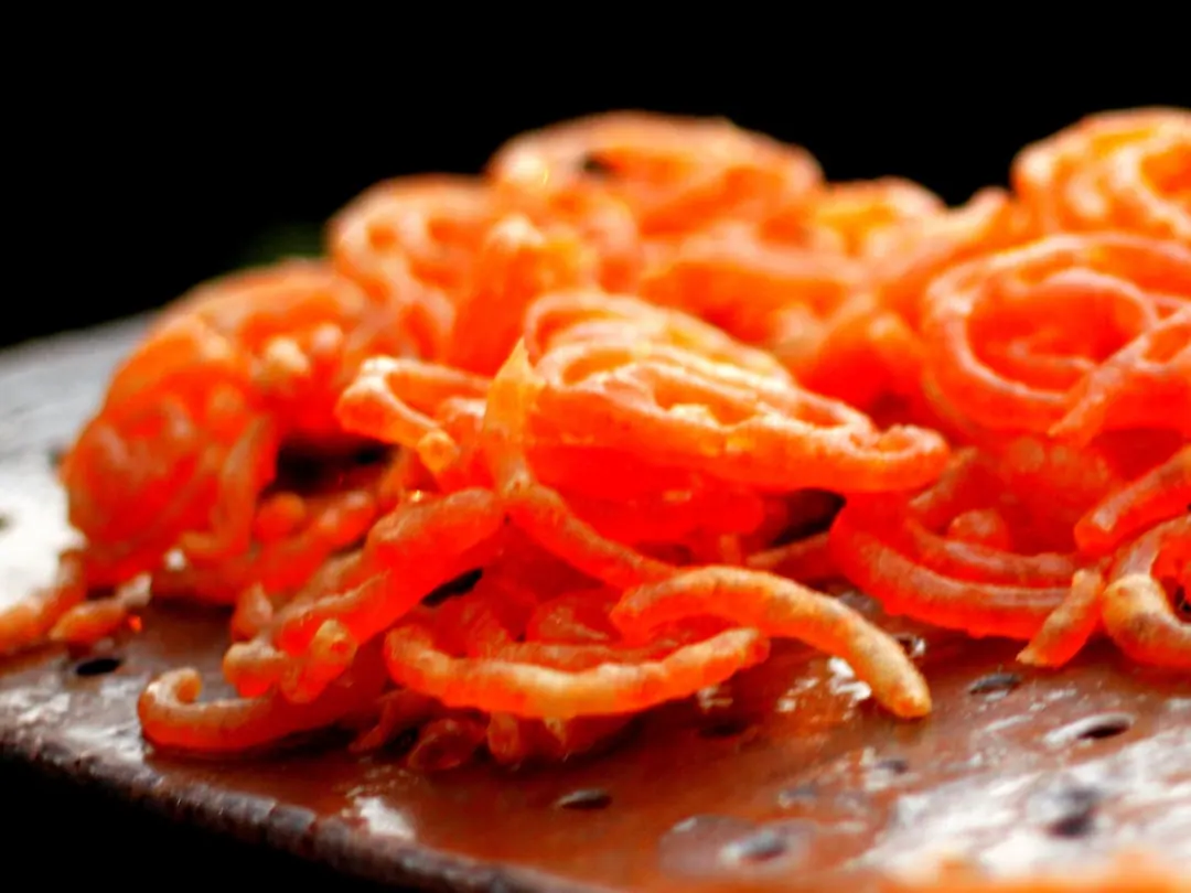 Bright orange spirals of fried batter glistening with syrup
